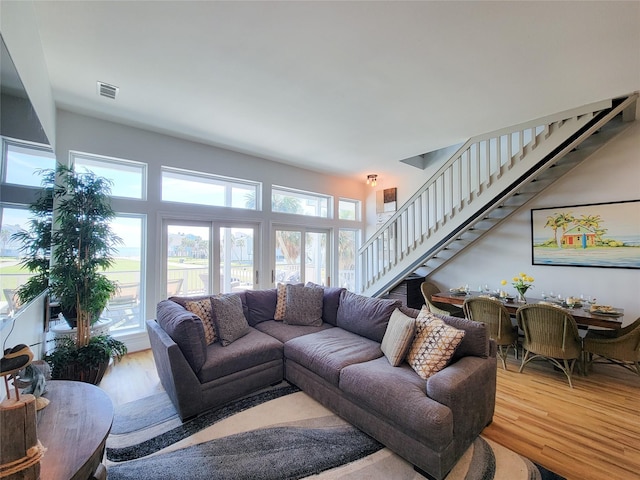 living area with stairs, visible vents, and wood finished floors
