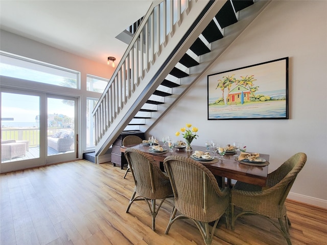 dining area with light wood-style flooring, baseboards, and stairs