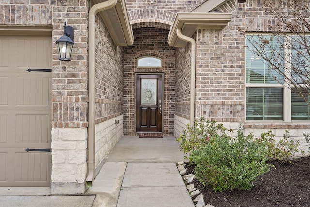 property entrance featuring a garage and brick siding