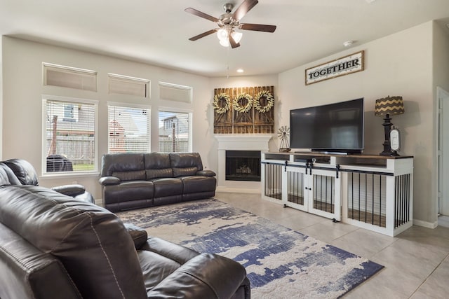 living area with a ceiling fan, a fireplace with raised hearth, baseboards, and tile patterned floors