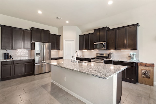 kitchen featuring light stone counters, visible vents, stainless steel appliances, and a sink