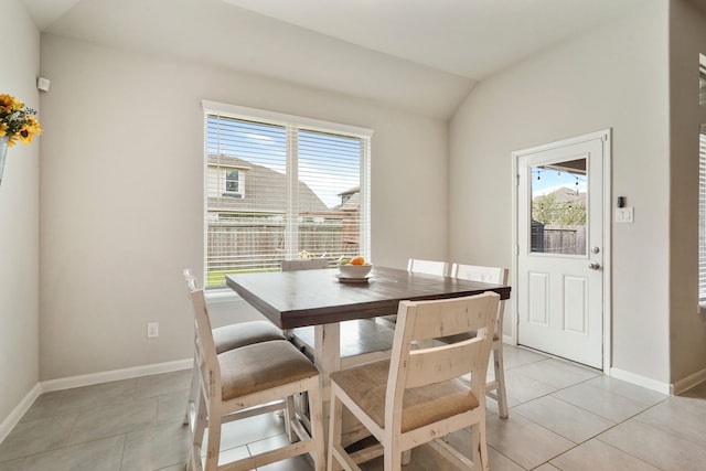 dining space with vaulted ceiling, baseboards, and light tile patterned floors