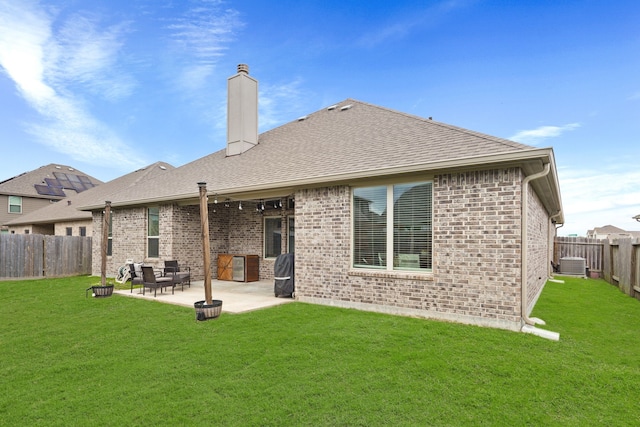 rear view of property with a yard, a fenced backyard, a patio, and a chimney