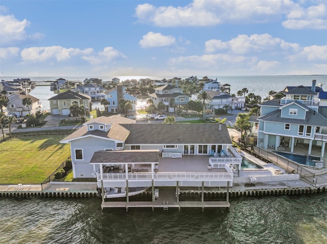 exterior space featuring a lawn, a deck with water view, fence, and a residential view