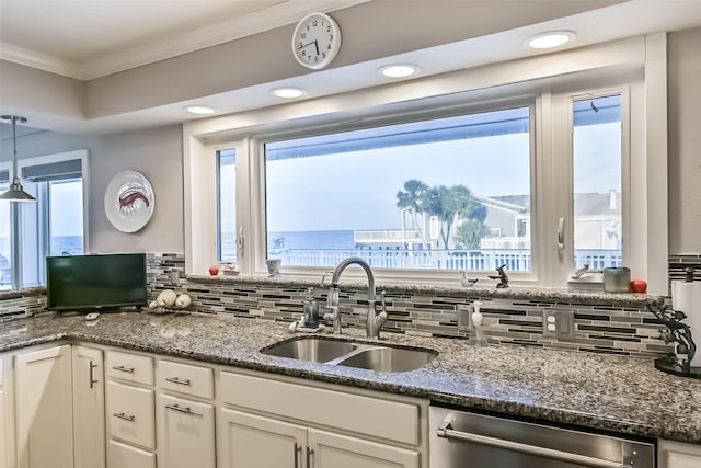 kitchen featuring backsplash, stainless steel dishwasher, ornamental molding, white cabinetry, and a sink