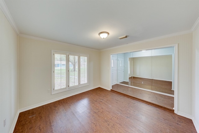 unfurnished bedroom with ornamental molding, wood finished floors, visible vents, and baseboards