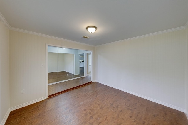 empty room featuring baseboards, wood finished floors, visible vents, and crown molding