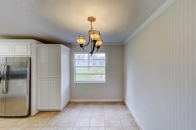 kitchen featuring crown molding, a notable chandelier, light tile patterned floors, freestanding refrigerator, and white cabinets