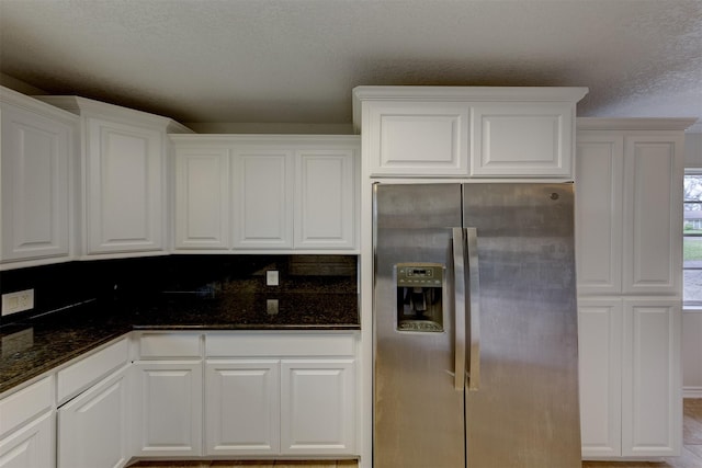 kitchen with dark stone counters, a textured ceiling, white cabinets, and stainless steel fridge with ice dispenser