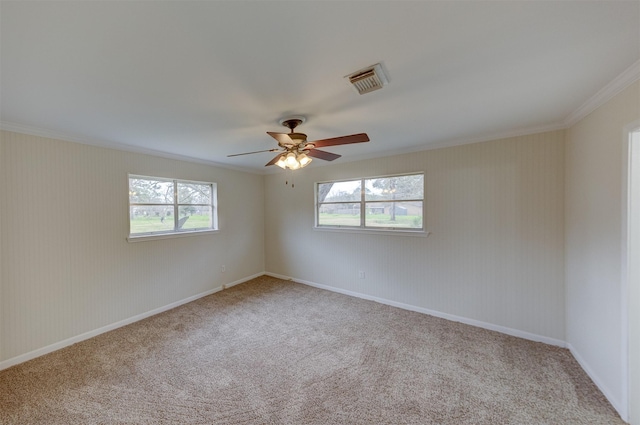 empty room with a ceiling fan, a wealth of natural light, visible vents, and carpet