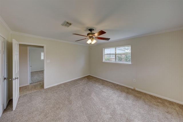 spare room with light carpet, ceiling fan, visible vents, and crown molding