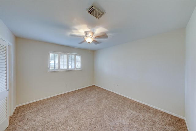 carpeted spare room featuring visible vents, ceiling fan, and baseboards