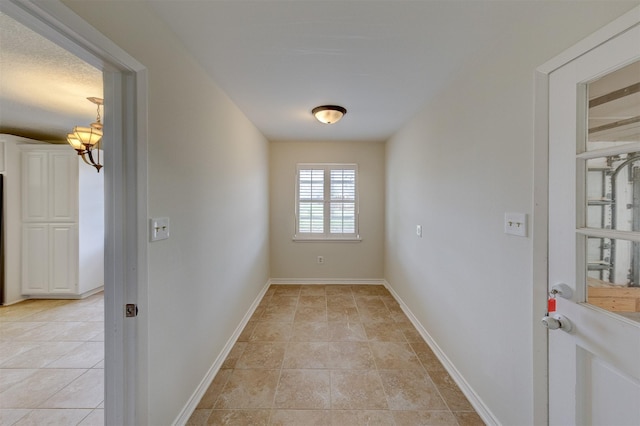 doorway with baseboards, a notable chandelier, and light tile patterned flooring