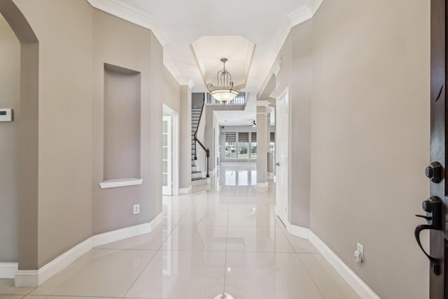 tiled foyer entrance featuring stairs, arched walkways, baseboards, and ornamental molding