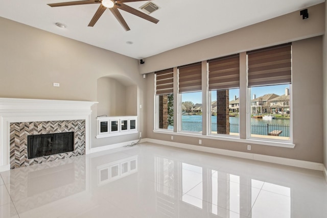 unfurnished living room featuring tile patterned flooring, visible vents, baseboards, a water view, and a tiled fireplace