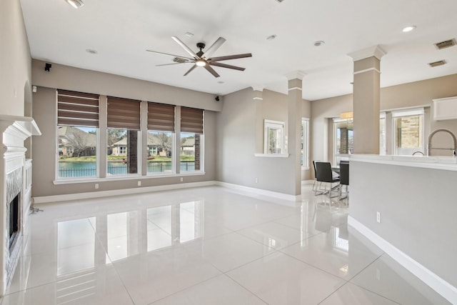 unfurnished living room featuring a wealth of natural light, visible vents, light tile patterned floors, and decorative columns