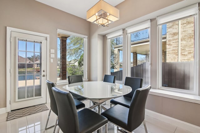 tiled dining space featuring a chandelier and baseboards