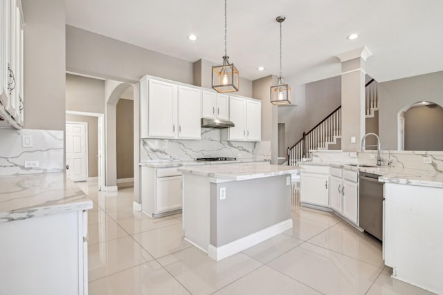 kitchen with under cabinet range hood, dishwasher, arched walkways, white cabinetry, and a sink