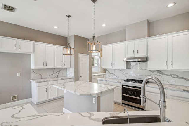 kitchen with light tile patterned floors, visible vents, under cabinet range hood, and a sink