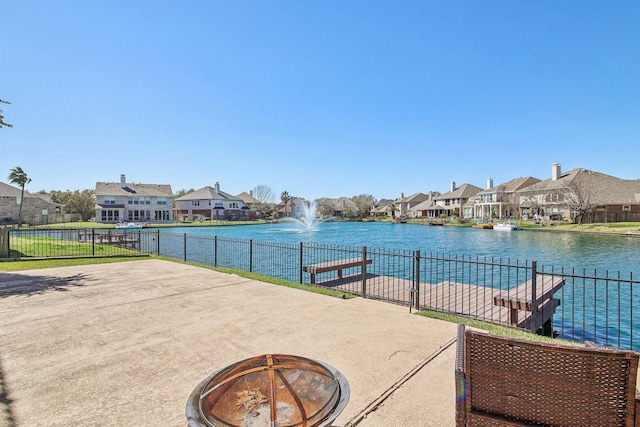 view of patio with a residential view, fence, and a water view