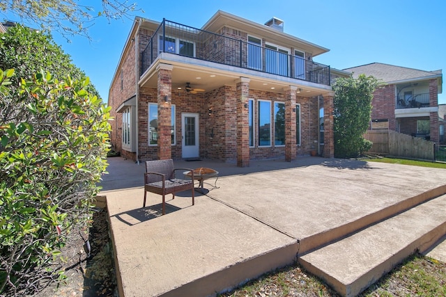 rear view of property with a fire pit, brick siding, ceiling fan, and a balcony