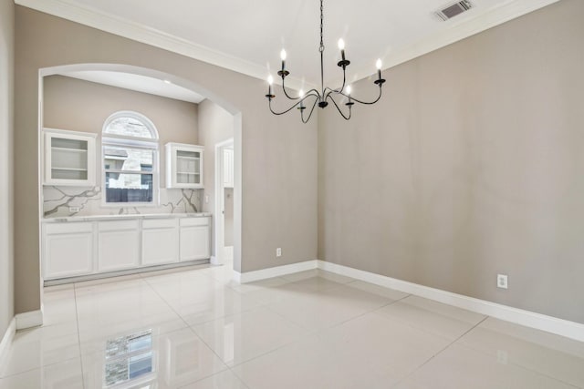 unfurnished dining area featuring baseboards, visible vents, light tile patterned flooring, arched walkways, and ornamental molding