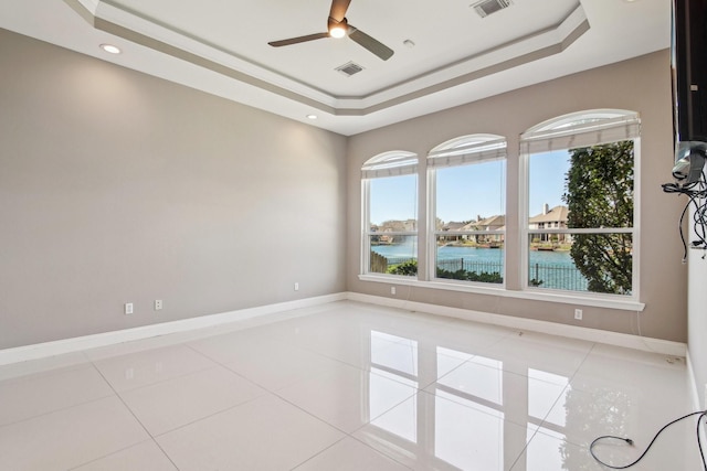 spare room featuring tile patterned flooring, a raised ceiling, baseboards, and visible vents