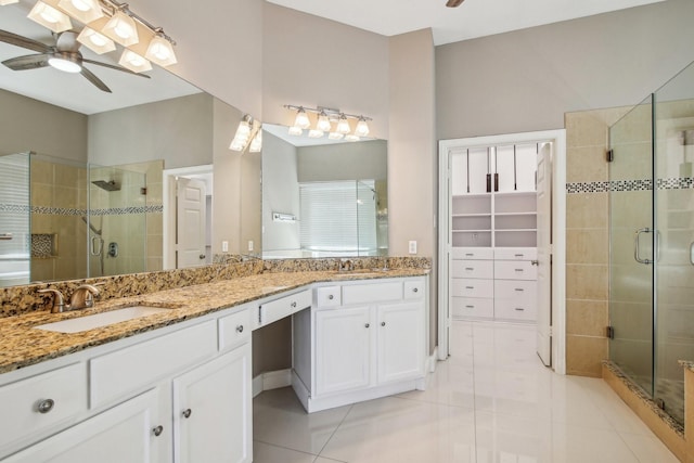 full bathroom featuring double vanity, a stall shower, ceiling fan, and a sink