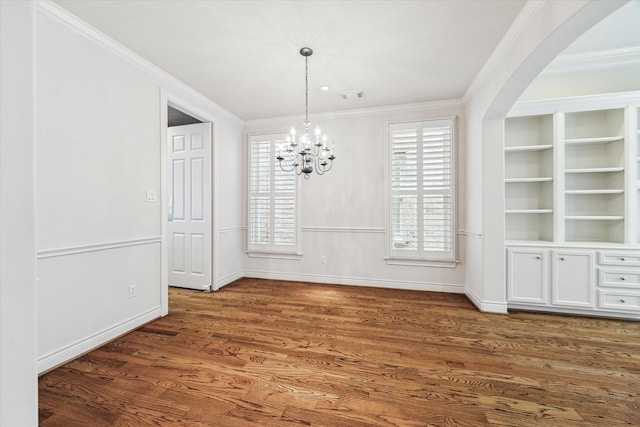 unfurnished dining area with built in features, crown molding, and wood finished floors