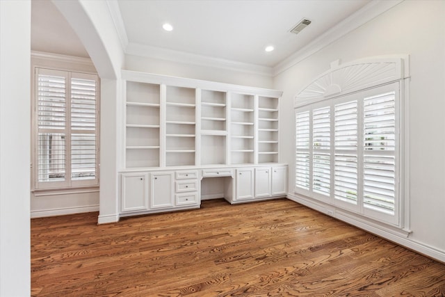 unfurnished office with visible vents, wood finished floors, built in study area, and ornamental molding