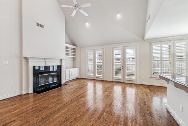 unfurnished living room featuring plenty of natural light, visible vents, wood finished floors, and a fireplace with flush hearth