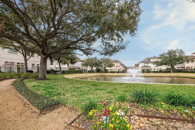 surrounding community with a residential view, a water view, fence, and a lawn