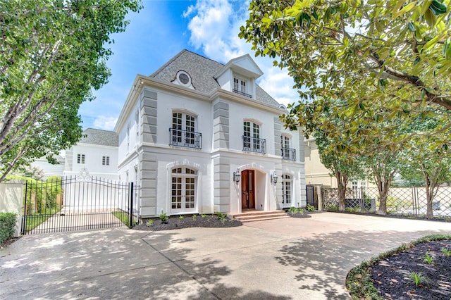 view of front of property with concrete driveway, french doors, fence, and a gate