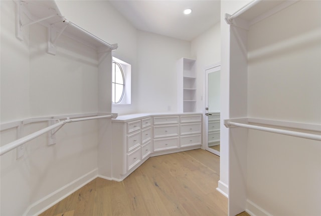 walk in closet with light wood finished floors