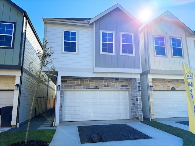 view of front of property featuring a garage, stone siding, and board and batten siding