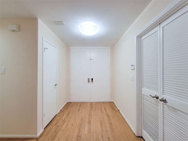 hall featuring light wood-style flooring and baseboards