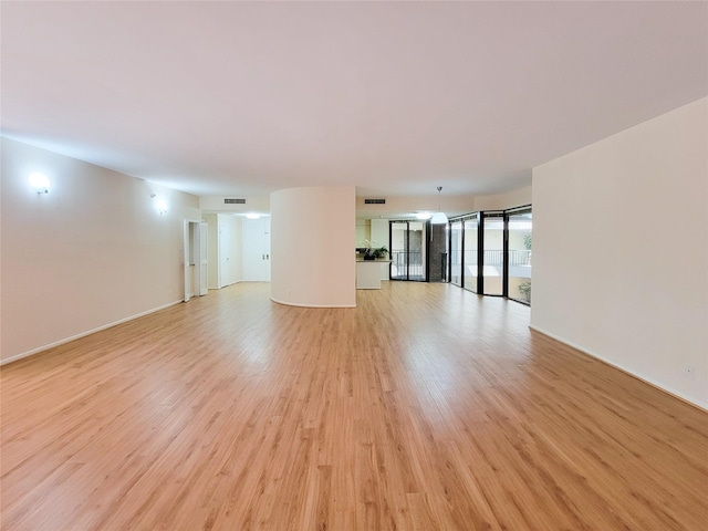 unfurnished living room with visible vents, light wood-style flooring, and baseboards