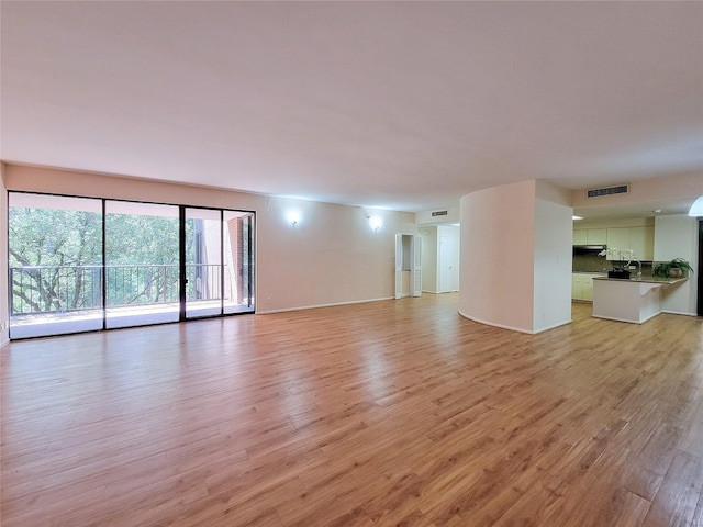 unfurnished living room with light wood-style floors, baseboards, and visible vents