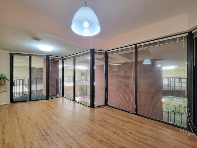 spare room with wood finished floors, visible vents, and floor to ceiling windows