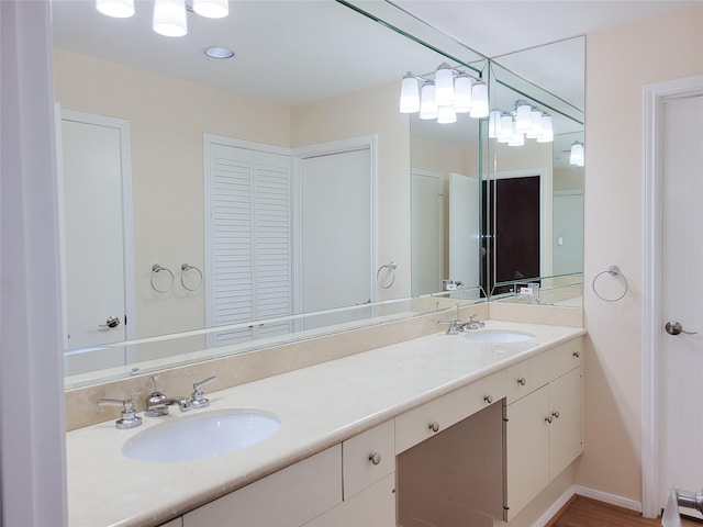 bathroom with a closet, a sink, baseboards, and double vanity