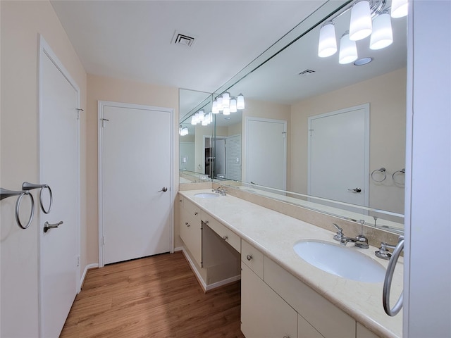 bathroom with double vanity, visible vents, a sink, and wood finished floors