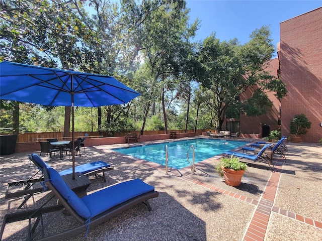 community pool featuring outdoor dining space, a fenced backyard, and a patio