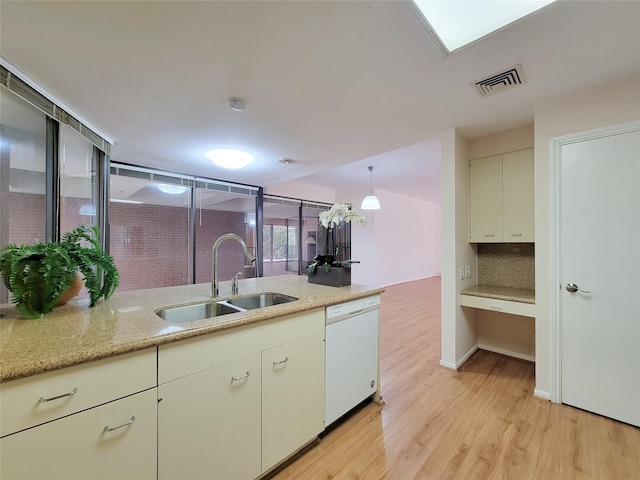 kitchen with visible vents, light wood-style flooring, decorative backsplash, white dishwasher, and a sink