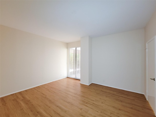 empty room with baseboards and light wood-style floors