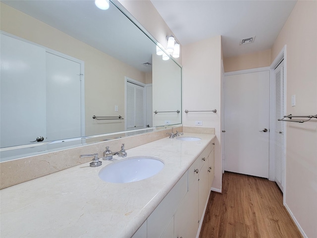 bathroom featuring double vanity, wood finished floors, a sink, and visible vents