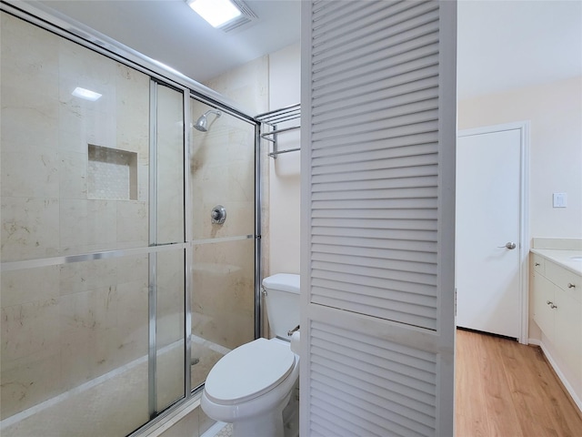 bathroom featuring toilet, a shower stall, wood finished floors, and vanity