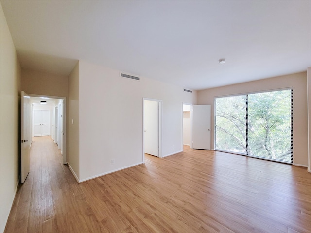 empty room with light wood-type flooring, baseboards, and visible vents