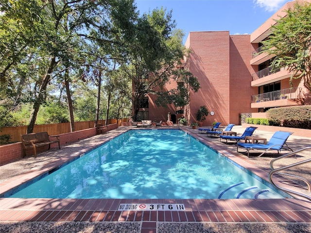 community pool with a patio area and fence