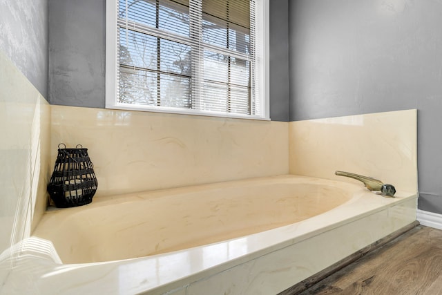 full bathroom with baseboards, wood finished floors, and a bath