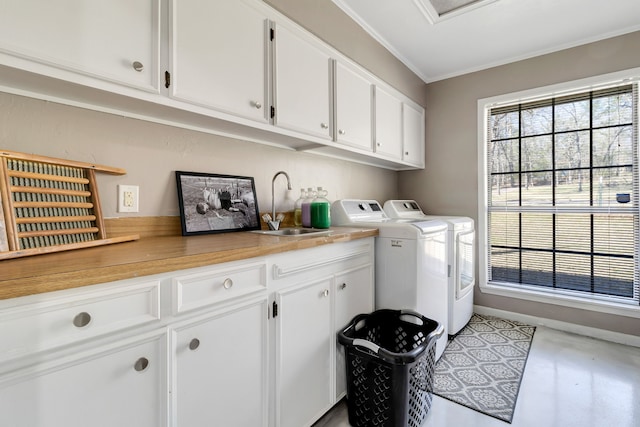 laundry room featuring a sink, baseboards, independent washer and dryer, cabinet space, and crown molding